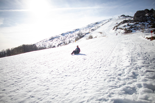 Father and son sledding together on a snowy hill.