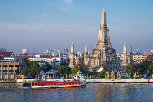 Ferry in front of the Wat Arun temple, otherwise known as the Temple of Dawn, located on the banks of the Chao Phraya River, Bangkok, Thailand.