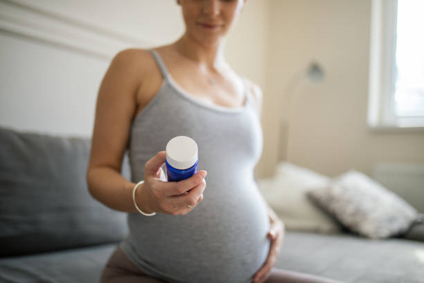 pregnant woman taking a medicine or nutritional supplement - herbal medicine vitamin pill capsule nutritional supplement imagens e fotografias de stock