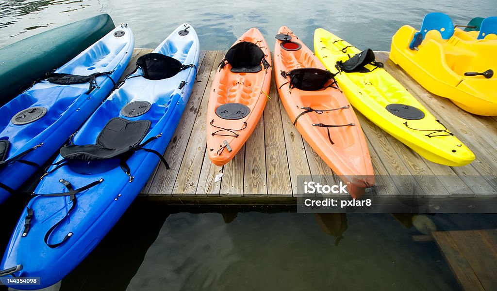 Kayaks and canoes on the dock Brightly colored kayaks and canoes on the dock Kayaking Stock Photo