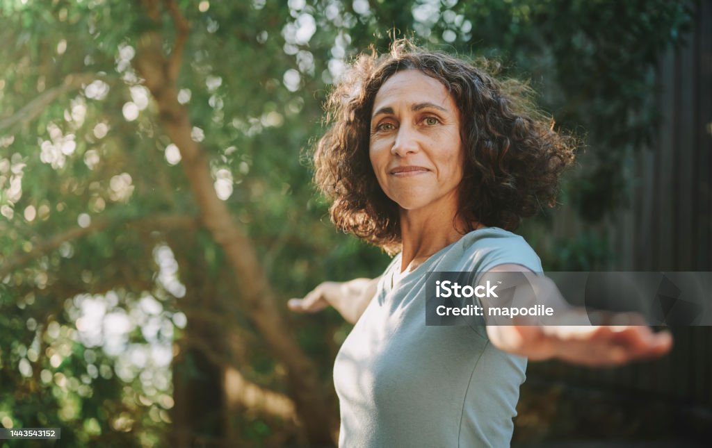 Smiling mature woman doing yoga outside in a park in summer Portrait of a smiling mature woman practicing yoga outside in a park in the summertime Yoga Stock Photo