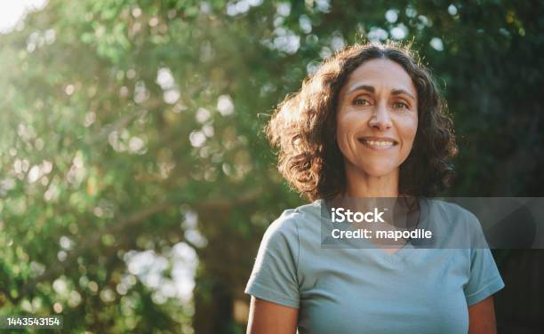 Smiling Mature Woman Standing In A Park Outdoors In The Summertime Stock Photo - Download Image Now