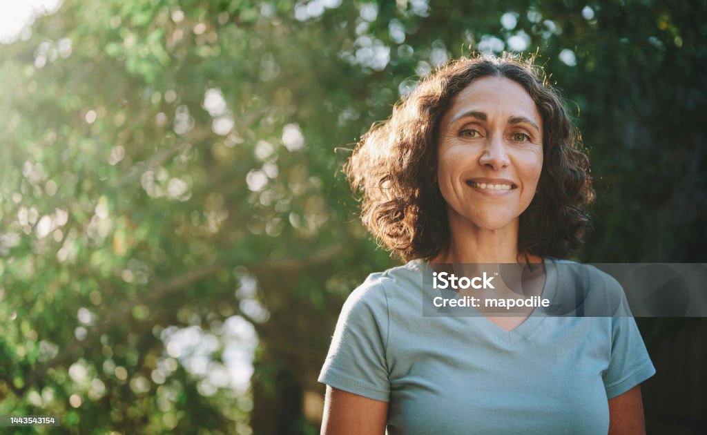 Mulher madura sorridente em pé em um parque ao ar livre no verão - Foto de stock de Mulheres royalty-free Mulher madura sorridente em pé em um parque ao ar livre no verão - Foto de stock de Mulheres royalty-free