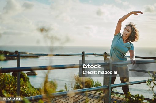 istock Fit mature woman stretching by the ocean before a run 1443543161