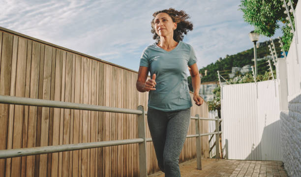 istock Fit mature woman smiling while running outside in summer 1443543309