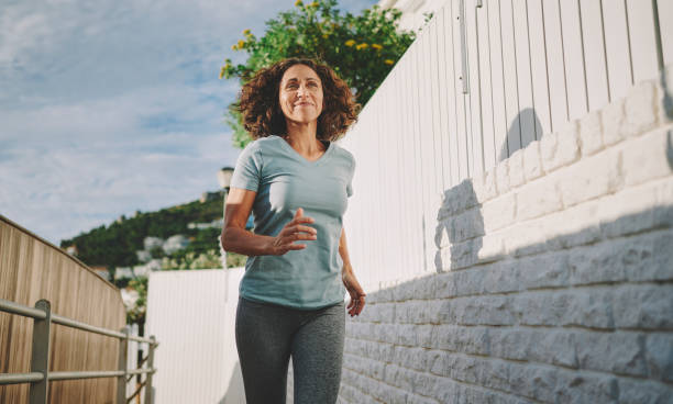 istock Smiling mature woman jogging along a sidewalk in summer 1443543337