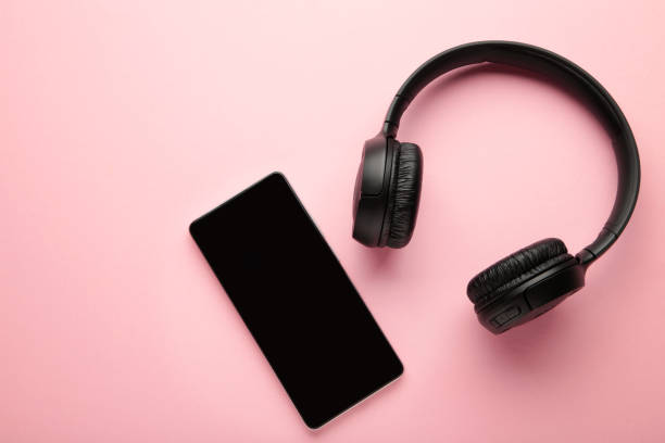 istock Black smartphone and wireless headphones on a pink background. 1443543352