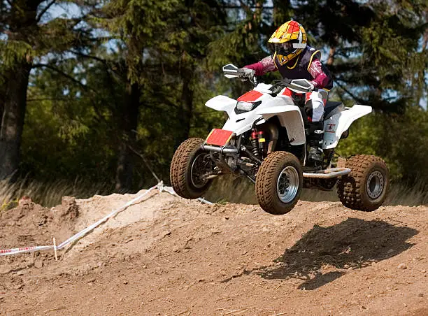 Young teenager jumping on his white new quad bike