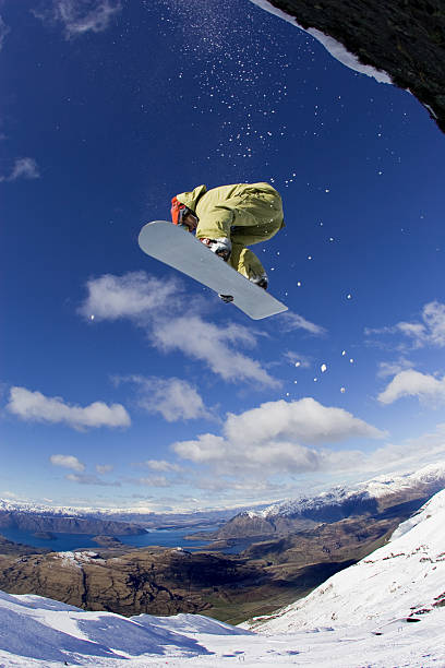 Snowboarder jumps through the blue sky stock photo