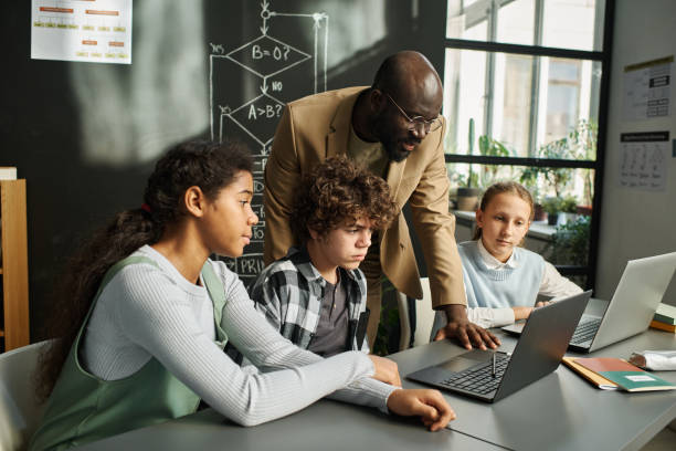 istock Teacher talking to children at IT lesson 1443547428