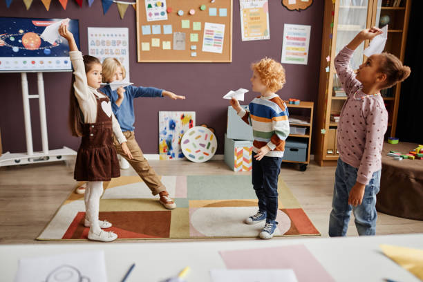 istock Group of multicultural little kids playing handmade paper airplanes 1443548728
