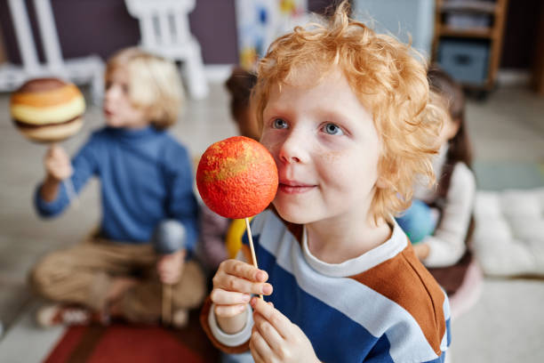 istock Adorable gingerhaired boy holding planet model of Mars 1443548896