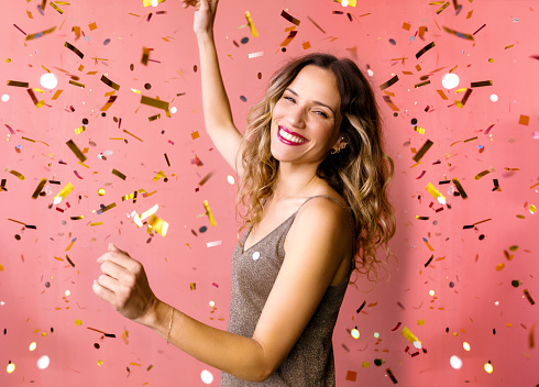 It's party time: A portrait of a cheerful attractive Caucasian female in glitter brown dress smiling while having fun. (studio shot, pink background)