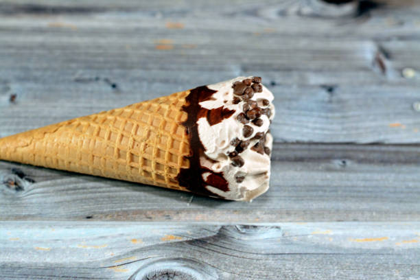 istock Ice cream vanilla cone with topping of chocolate chips pieces in a crispy wafer cones, selective focus of melting cold ice cream twirl in a wafer biscuits 1443552449