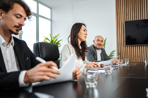 Happy group of successful business people talking in a meeting at the office. **DESIGN ON DOCUMENTS AND SCREEN BELONGS TO US**