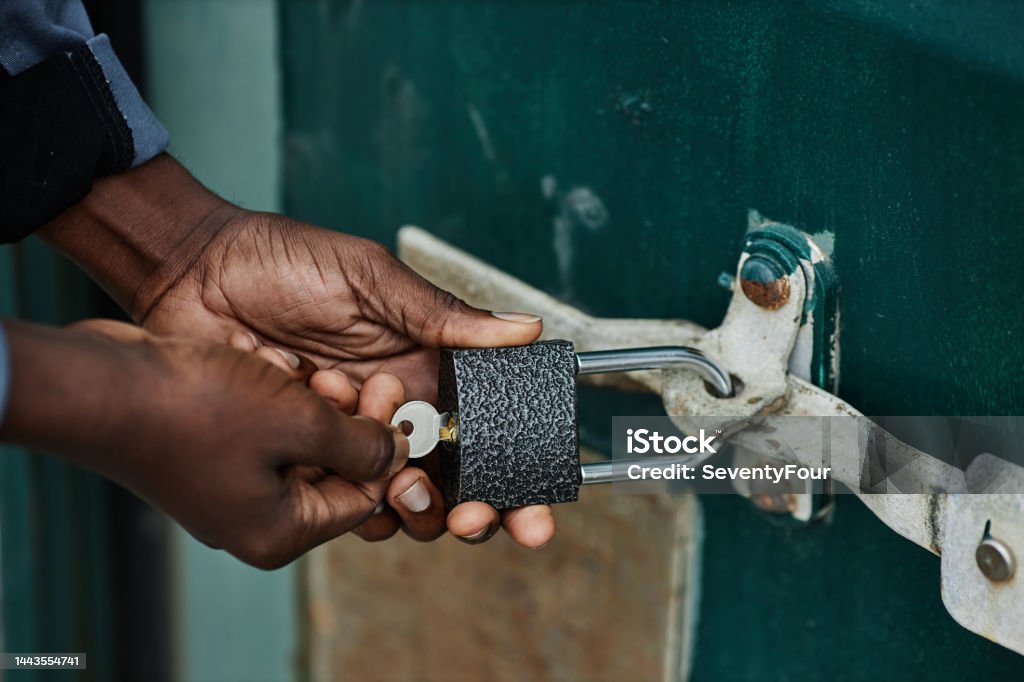 Close up of male hands opening lock Close up of male hands opening lock on container door in shipping docks, copy space Locking Stock Photo