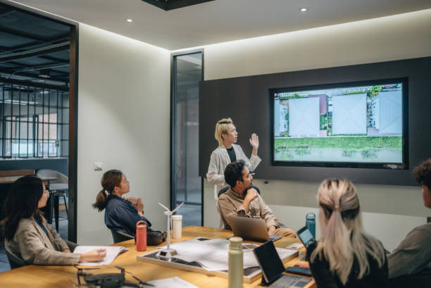 Business person presentation on solar cell panel technology at meeting room. LGBTQIA Person is chief executive talking to a diverse team of professional businesspeople at office conference room. sustainable business stock pictures, royalty-free photos & images