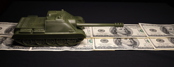 Tank on dollar bills. The concept of war costs, military spending. Horizontal banner