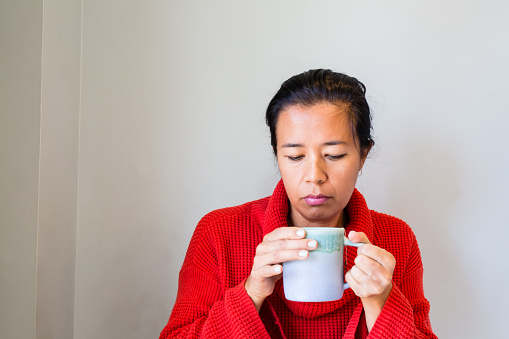 Woman in a red sweater holds a mug with tea in it