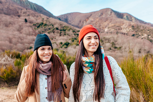 Two young beautiful hiker women on the top of mountain looking away - Happy smiling sisters enjoying together - Hiking and climbing cliff