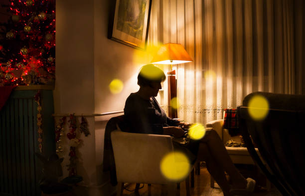 An elderly woman makes Christmas presents and ornaments for her grandchildren.  She sitting on a armchair.
