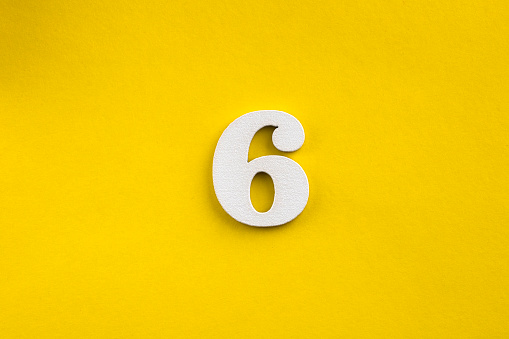 Number six - white number in wood on yellow background