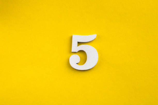 istock Number five - white number in wood on yellow background 1443563810