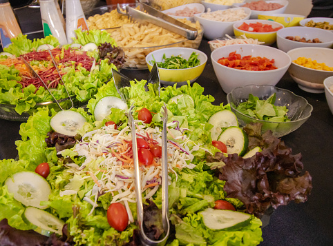 Plate of salad with lettuce, tomatoes and various leaves on the table