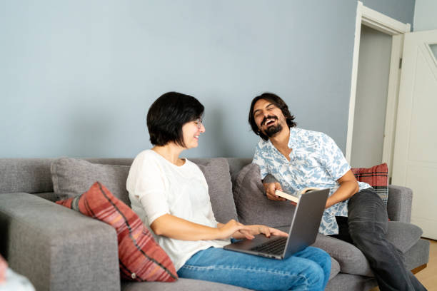 istock Happy young couple using a laptop while relaxing on a couch at home 1443565837