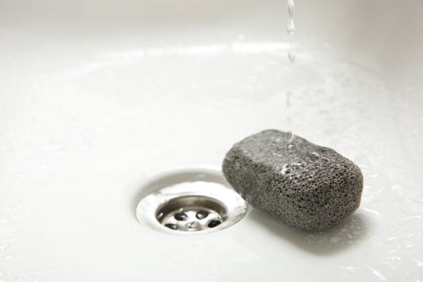 istock Pouring water onto pumice stone in sink, space for text 1443566857