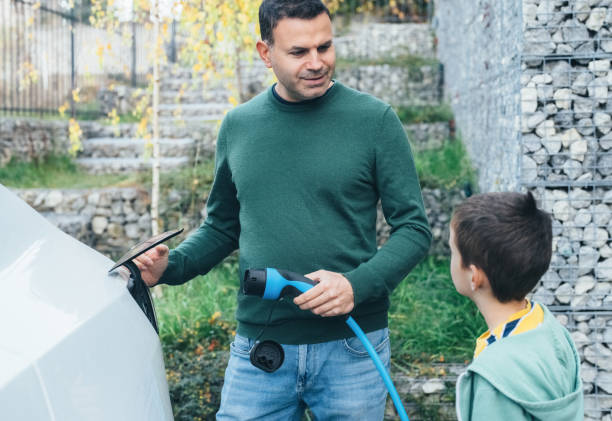 istock Father and son charging new electric car at home 1443567111