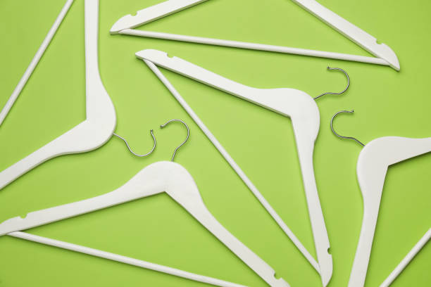 istock Empty clothes hangers on green background, flat lay 1443568424