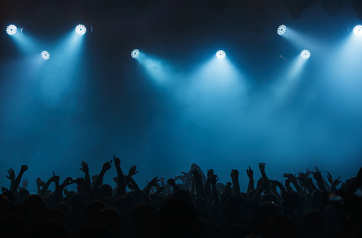 Background with concert crowd hands. Wallpaper with empty stage on music festival. Illuminated scene on popular musical event
