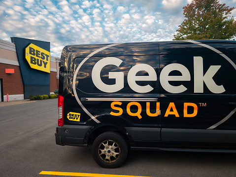 New Hartford, New York - Oct 1, 2022: Landscape Wide View of Geek Squad Black Van in the Foreground and Best Buy Building in Background.