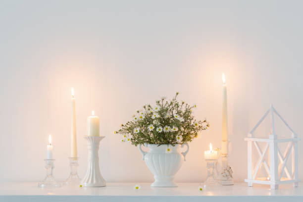 istock white flowers in white ceramic vase with burning candles in white interior 1443572219