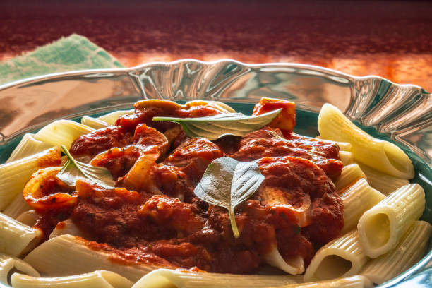 A plate of delicious pasta in the kitchen with tomato sauce and grated cheese on it