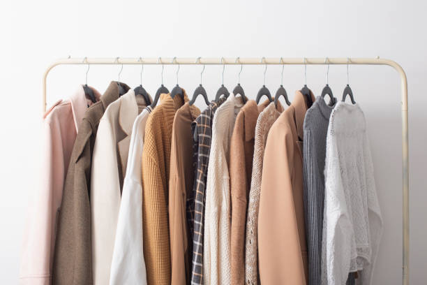 female autumn clothes on hangers  in  white room stock photo