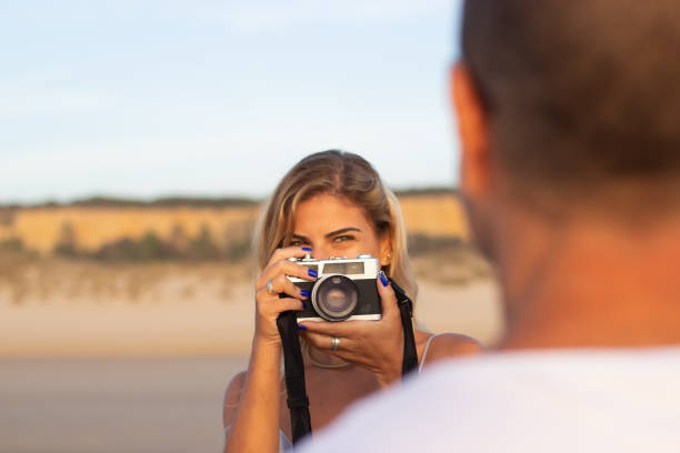 istock Playful woman photographing husband on beach 1443576302