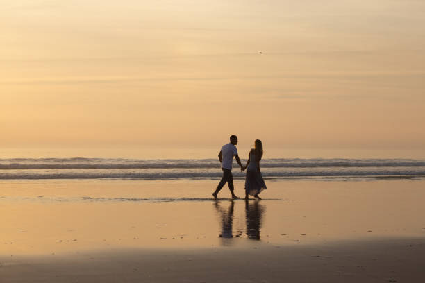 istock Loving couple walking on beach at sunset 1443576362