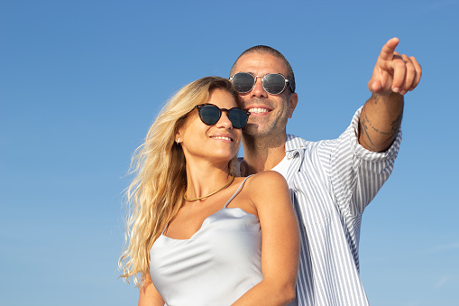 Portrait of trendy Caucasian couple at beach. Husband and wife hugging, travelling in hot country. Portrait, vacation, beauty, relationship concept