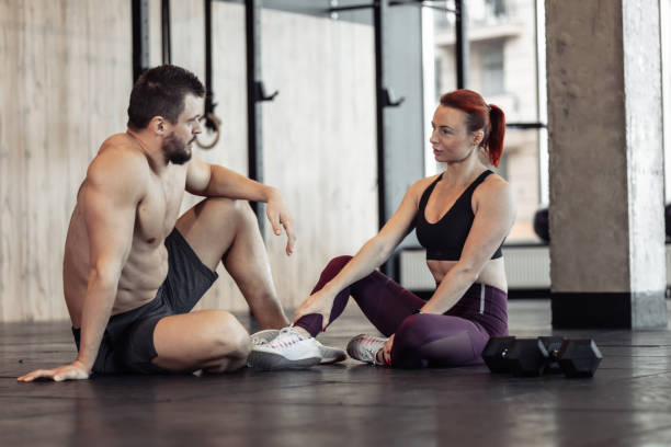 istock Athletic couple talking while sitting on the floor in the gym. Interaction, communication, healthy lifestyle, bodybuilding and fitness 1443576742