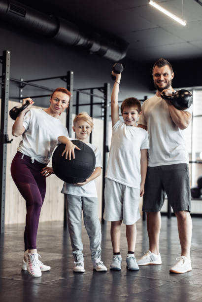 healthy family concept. mom, dad and two sons teenagers with sports equipment posing in gym. spending time together, active lifestyle - small gymnastics athlete action imagens e fotografias de stock