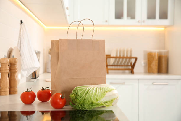 istock Paper shopping bag and fresh vegetables on white countertop in kitchen. Space for text 1443577512
