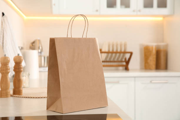 istock Paper shopping bag on white countertop in kitchen. Space for text 1443578740
