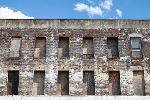 The exterior of an old brick building with boarded up windows in Brooklyn of New York City