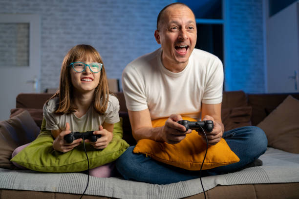 padre e figlia giocano ai videogiochi - video game family child playful foto e immagini stock