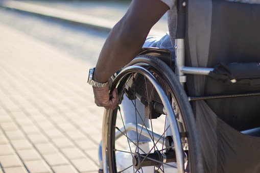 Confident young Caucasian male in a wheelchair going to a business meeting. He is moving and looking away.