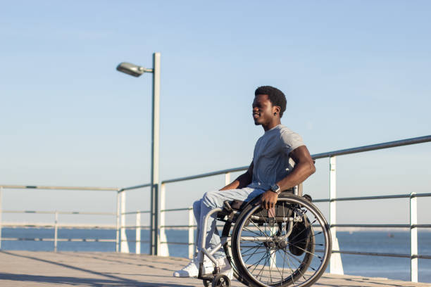 istock Young Black man in wheelchair enjoying spending time at seashore 1443581504