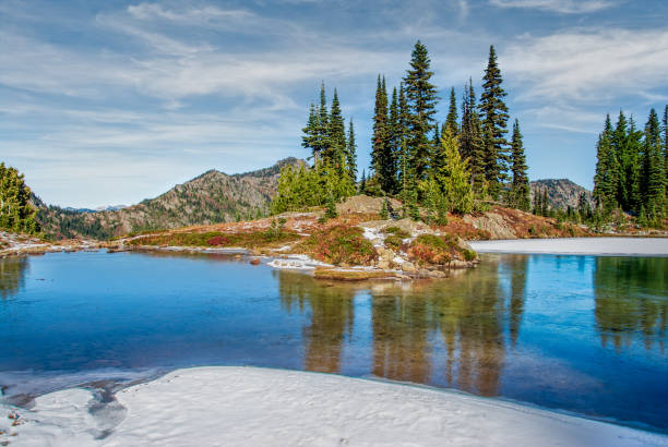The Pacific Crest Trail, officially known as the Pacific Crest National Scenic Trail, stretches 2,653 miles from the Mexican border to the Canadian Border.  It follows the Cascade Range of mountains in Washington, Oregon and Northern California.  In Southern California it follows the Sierra Nevada range.  The mountains, lakes, meadows and forests along the Pacific Crest Trail are a visual delight in any season.  This scene of an alpine tarn surrounded by snow was photographed near Chinook Pass in the William O. Douglas Wilderness, Washington State, USA.