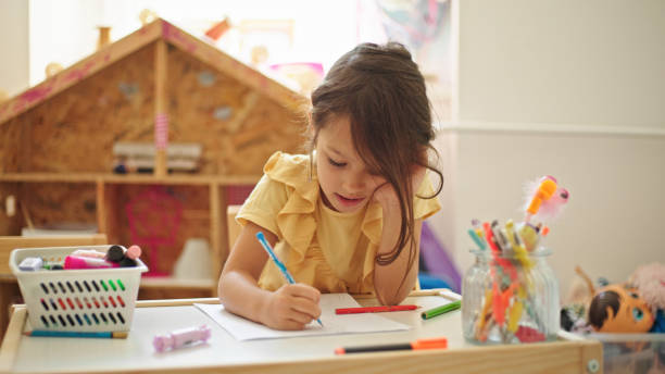 istock Little girl drawing while sitting at the table in her room 1443584645